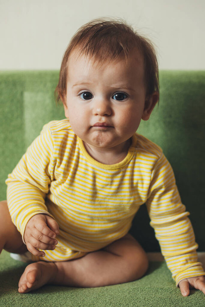 Baby girl sitting on sofa at home in the living room and looking at camera. Lifestyle concept. - Foto, immagini