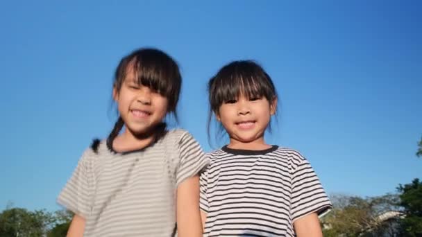 Heureux asiatiques frères et sœurs filles câlins dans le jardin d'été sur un fond de ciel lumineux. Portrait de petite fille souriante dans le parc. - Séquence, vidéo