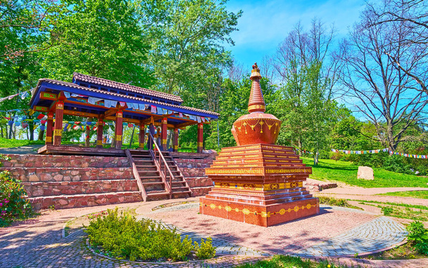 Ogród Tybetański z kolorowymi flagami buddyjskimi, drewniana Gazebo do medytacji i kamienny Chorten za nim, Kijowski Ogród Botaniczny, Ukraina - Zdjęcie, obraz