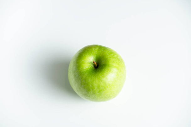 een hele groene appel op een witte achtergrond - Foto, afbeelding