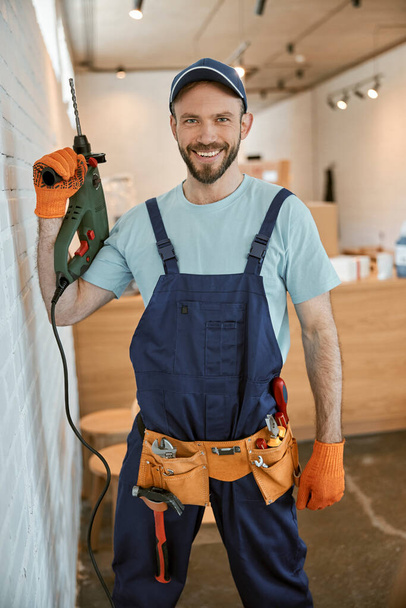 Веселый работник с электрическим молотком в руках - Фото, изображение