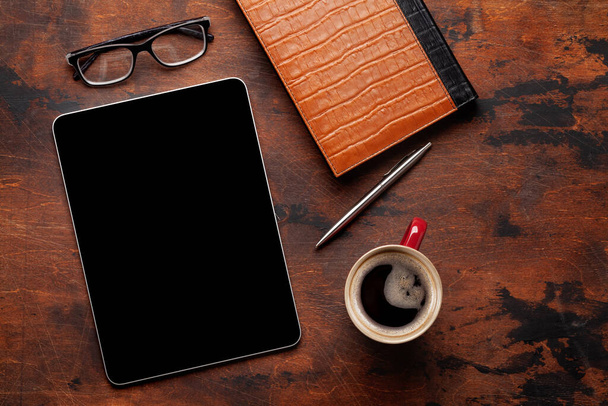 Tableta con pantalla en blanco en el escritorio, taza de café y suministros de oficina. Vista superior plano con espacio de copia - Foto, imagen