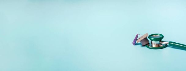 Absolventenmütze mit Stethoskop und Zahlen 2022 auf blauem Hintergrund, Nahaufnahme mit Kopierraum. Medizinisches Ausbildungskonzept. - Foto, Bild