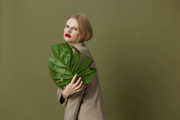 glamorous woman red lips holding  palm leaf  posing. High quality photo - Foto, afbeelding