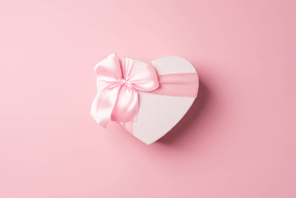 Top view photo of valentine's day decorations heart shaped giftbox with pink ribbon bow on isolated pastel pink background with copyspace - Photo, Image