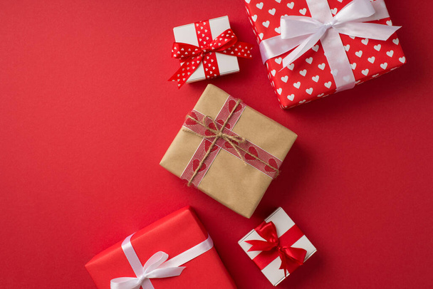 Top view photo of st Walentynki 's dekoracje prezentuje pudełko z papieru rzemieślniczego prezent wstążką i sznurkiem łuk na izolowanym czerwonym tle z copyspace - Zdjęcie, obraz