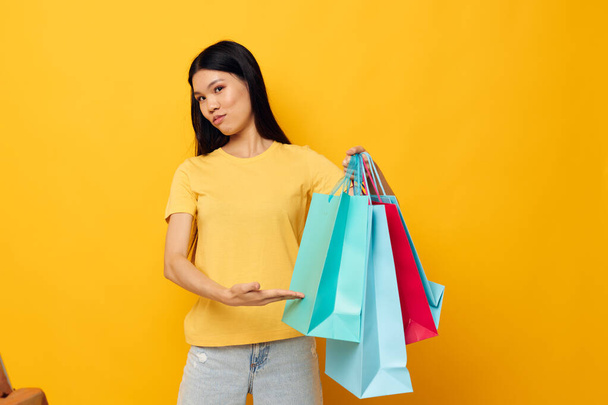 woman with Asian appearance with packages in hands shopping isolated background unaltered - Φωτογραφία, εικόνα