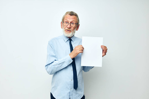 Portrait elderly man holding documents with a sheet of paper cropped view - Fotó, kép