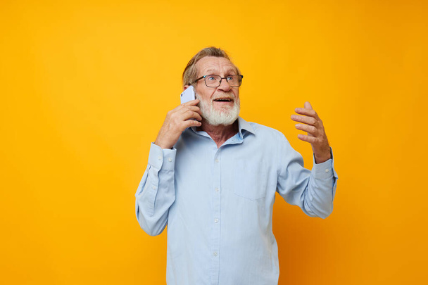 Portrait of happy senior man in a blue shirt and glasses talking on the phone cropped view - Photo, Image
