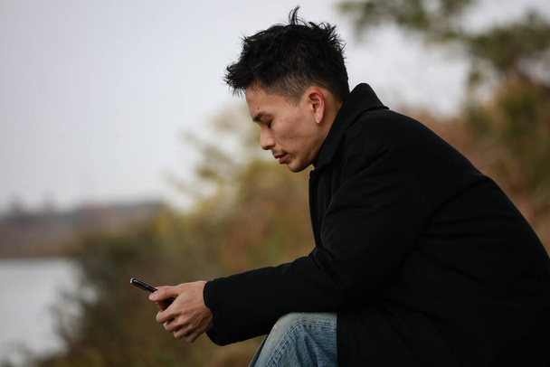 young asian man using smartphone on background - Foto, imagen