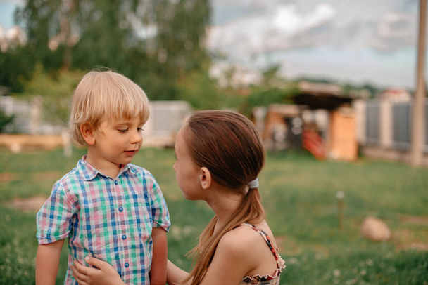 Portrait of little boy and girl walking in the park, nice summer weather. Carefree childhood. Brother and sister have fun outdoors together. Little boy with blond hair and blue eyes. - Fotó, kép