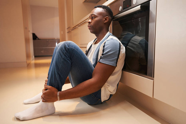Sad multiethnic man sitting in the kitchen - Foto, afbeelding