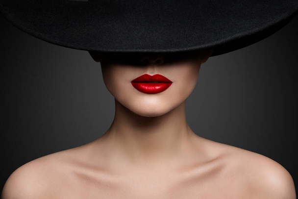 Red Lips Make up Closeup. Mysterious Fashion Woman Face Hidden by Black brimmed Hat. Elegant Retro Lady Fine Art Portrait over Gray Background - Fotoğraf, Görsel