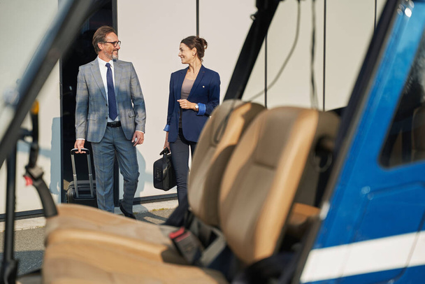 Two joyous people with luggage approaching chopper - Fotoğraf, Görsel