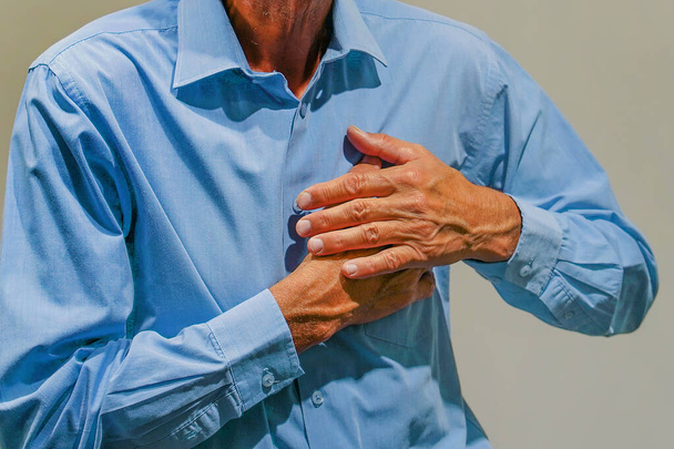 Senior man suffering from heart attack. Closeup shot of a mature man holding his chest in discomfort - Fotó, kép