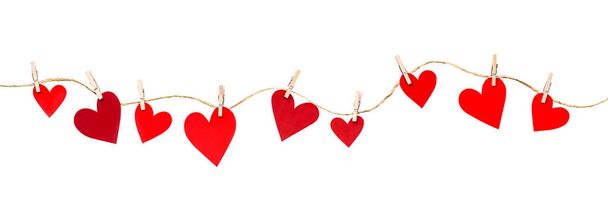 slinger van harten op wasknijpers op een witte geïsoleerde achtergrond, decoratie voor Valentijnsdag - Foto, afbeelding