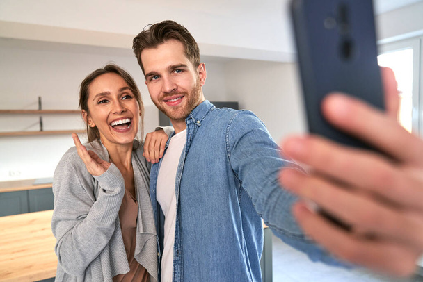Very excited caucasian couple taking selfie in their new flat - Zdjęcie, obraz