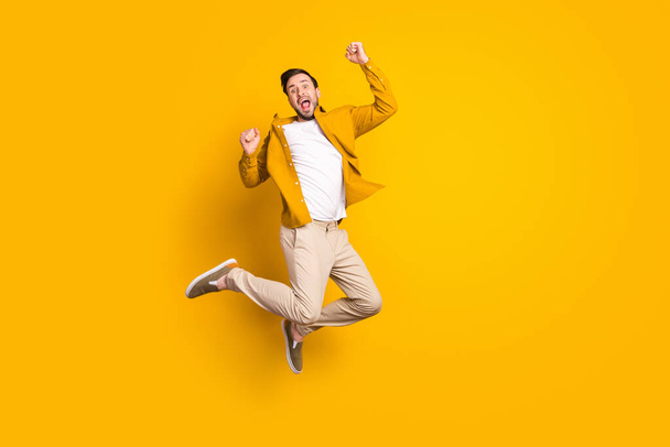 Full length photo of sweet happy gentleman dressed casual outfit smiling jumping high rising fists isolated yellow color background. - Foto, Bild