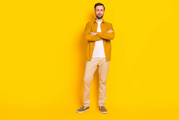 Full length φωτογραφία του γλυκού αυτοπεποίθηση νεαρός κύριος ντυμένος casual ρούχα στέκεται τα χέρια διπλωμένα απομονωμένο κίτρινο χρώμα φόντο. - Φωτογραφία, εικόνα