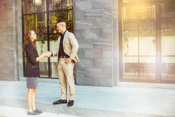 オフィスの外の屋外設定で若いビジネスマン、ハンサムな男性と美しい女性の握手挨拶、非公式に:スペースをコピー - 写真・画像