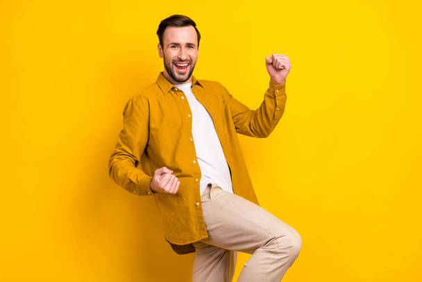 Profile side photo of young handsome man happy positive smile rejoice victory fists hands isolated over yellow color background. - Photo, image