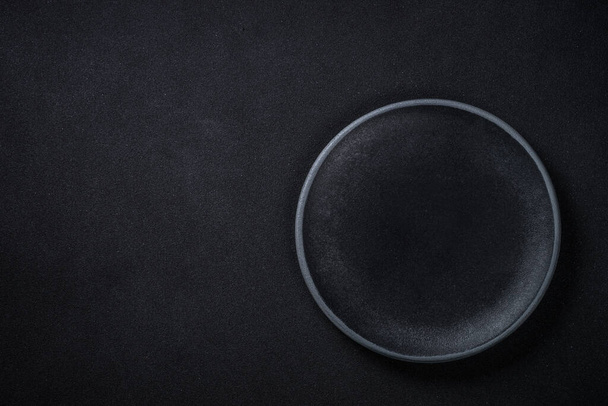 Black plate at black background. Top view. - Fotoğraf, Görsel