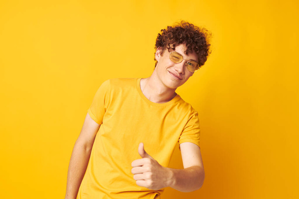 guy with red curly hair yellow t-shirt glasses fashion hand gestures yellow background unaltered - Fotó, kép