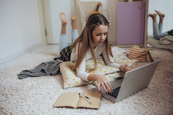 Дівчина-підліток з ноутбуком у своїй кімнаті
. - Фото, зображення