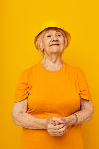 Photo of retired old lady in yellow t-shirts hat posing cropped view - Zdjęcie, obraz