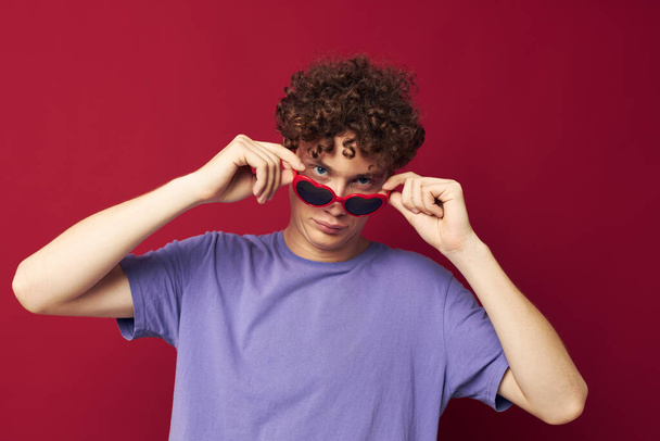 cute red-haired guy hand gestures heart shaped glasses posing red background - Foto, afbeelding