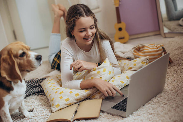 Дівчина-підліток з ноутбуком у своїй кімнаті
. - Фото, зображення