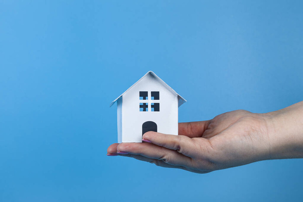 Rent apartments, Real Estate and buying a house idea. Blue background.Hand with a toy house. - 写真・画像