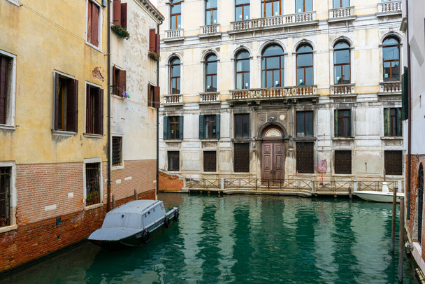 2 december 2021 - Venetië, Italië: Huizen gebouwd aan de grachten van Venetië met een eigen boot afgemeerd. - Foto, afbeelding