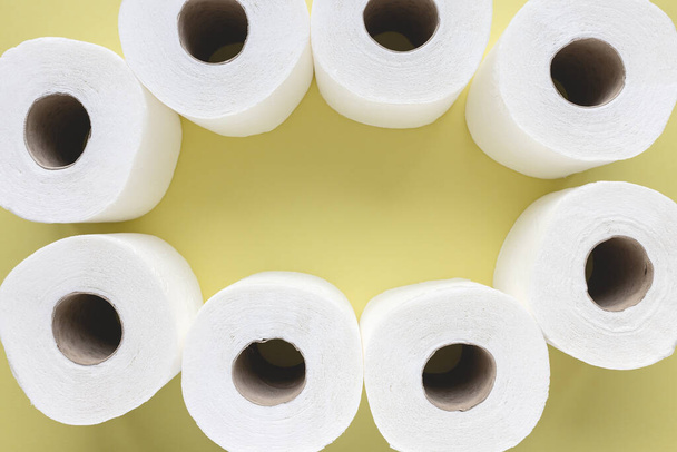 New white toilet paper rolls on yellow background - Fotó, kép