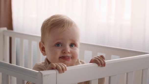 close-up schot van schattige baby staande in zijn wieg en grimmig - Video