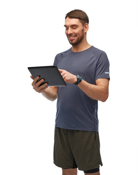 mosolygós férfi sport ruhák gazdaság tabletta pc - Fotó, kép