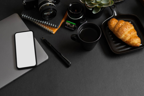 Black office desk background with office supplies, devices and smartphone blank screen mockup. - Foto, afbeelding