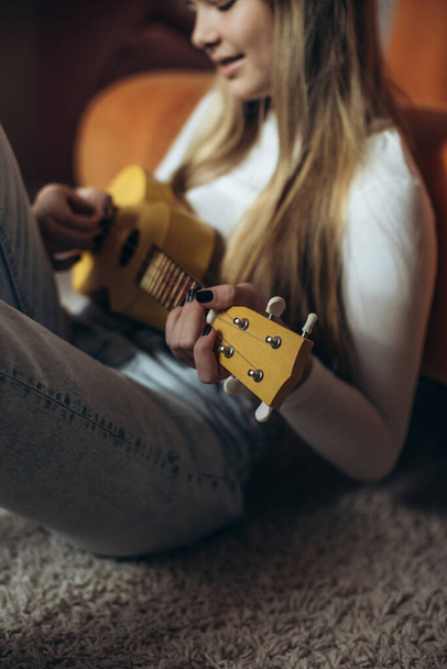10代の女の子がギターを弾くことを学んでいる、ウクレレ. - 写真・画像