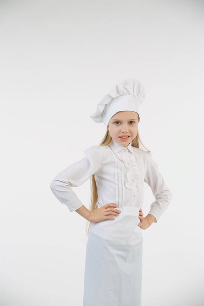 Niña en edad escolar vestida de cocinera en blanco. Un sujeto independiente. Concepto de profesión y actividad. - Foto, imagen