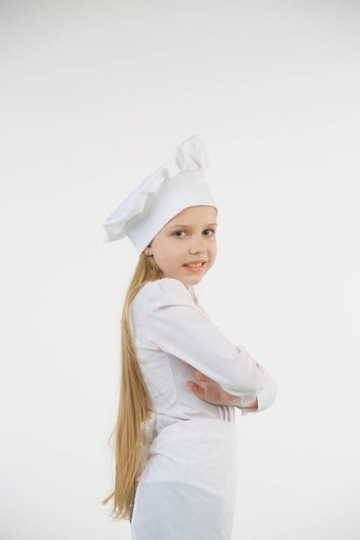 Дівчина шкільного віку, одягнена як кухарка в біле. Автономна тема. Концепція професії та діяльності
. - Фото, зображення