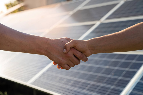 Two people having a shaking hands against solar panel  after the conclusion of the agreement in the renewable energy   - Zdjęcie, obraz