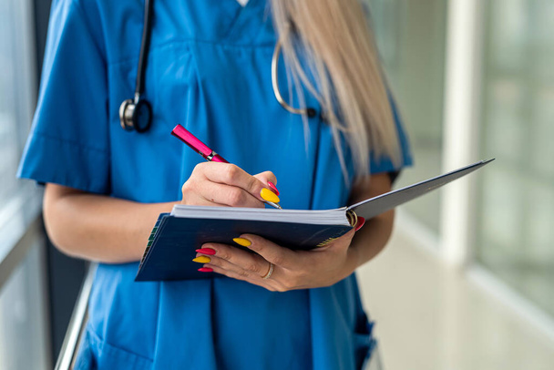 jeune belle infirmière se tient dans le couloir avec un stéthoscope et une tablette. Concept de médecine - Photo, image