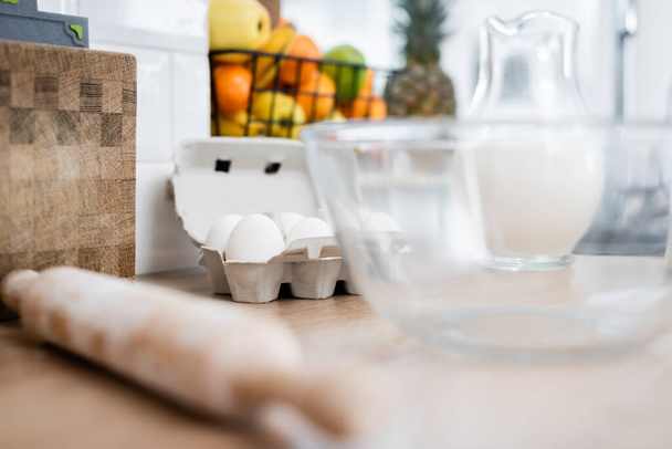 Eggs, blurred rolling pin and milk in kitchen  - Foto, imagen