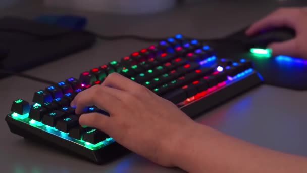 Bir esport oynatıcısı RGB arka ışığı olan bir oyun klavyesinde ve farede oyunlar oynar - Video, Çekim