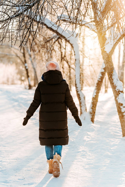 Une jeune belle femme marche sur un sentier dans une forêt enneigée d'hiver - Photo, image