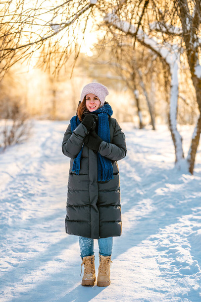 A young beautiful woman walks on a path in a snowy winter forest - Фото, изображение