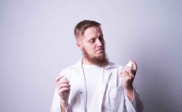 man arts in laboratorium jas op grijze achtergrond van toepassing crème op handen - Foto, afbeelding