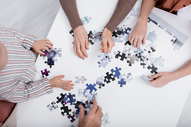 top view of cropped family playing jigsaw puzzle game on table - Fotografie, Obrázek