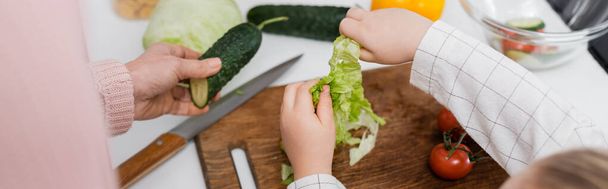 top view of cropped woman and child near fresh vegetables on kitchen table, banner - 写真・画像