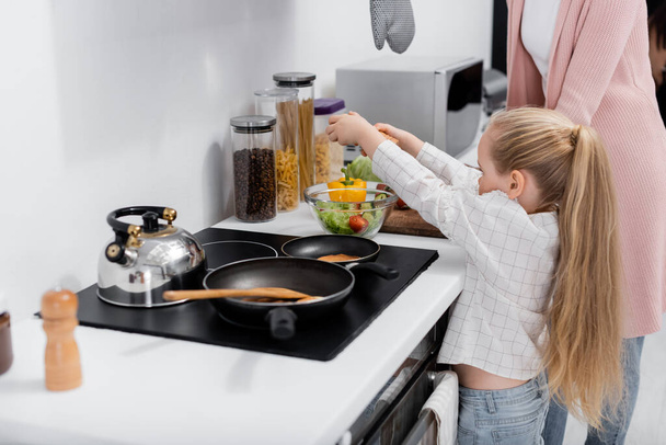 érett nő kis unokája készül saláta a konyhában  - Fotó, kép